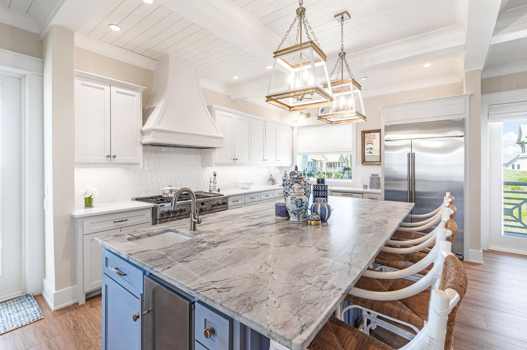 Kitchen with a blue island, stone counters and lantern pendants