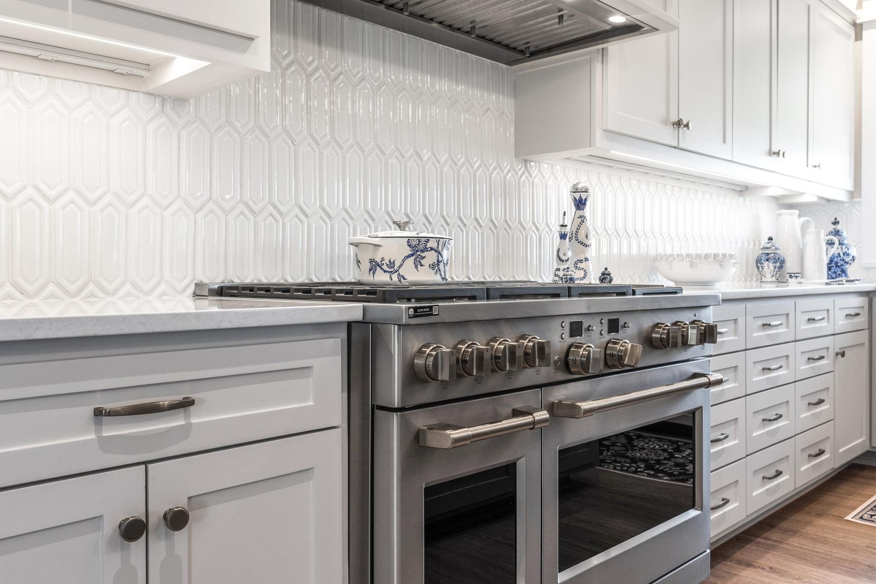 A chef's range wall with a professional range and white tile in a custom coastal kitchen