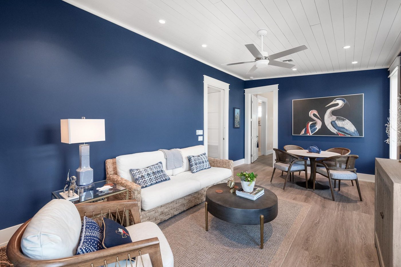 Sitting room with deep navy walls and coastal artwork