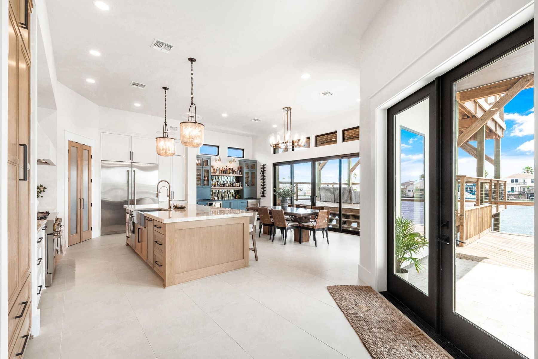 An open kitchen and dining room with white oak cabinetry, looking out to the canal