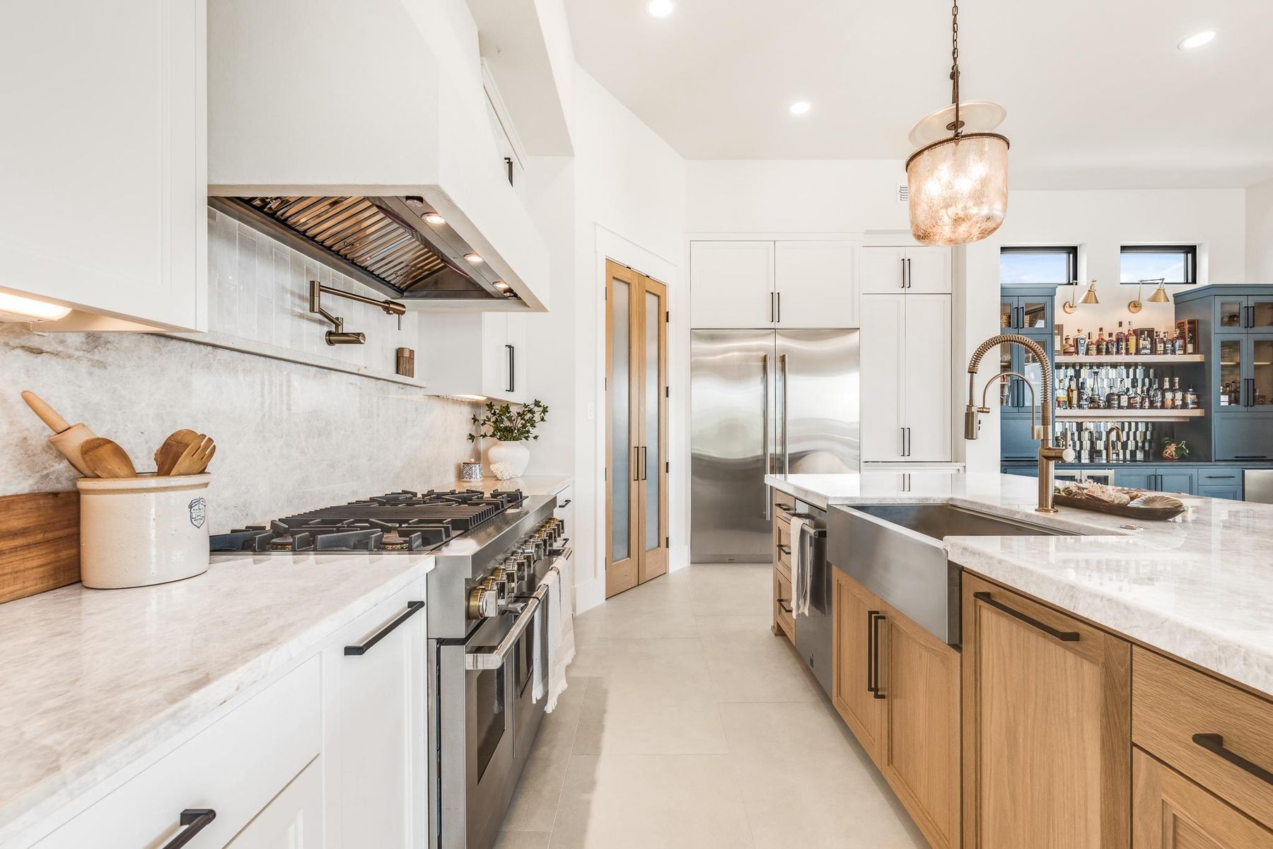Kitchen with light oak cabinetry and lantern pendants