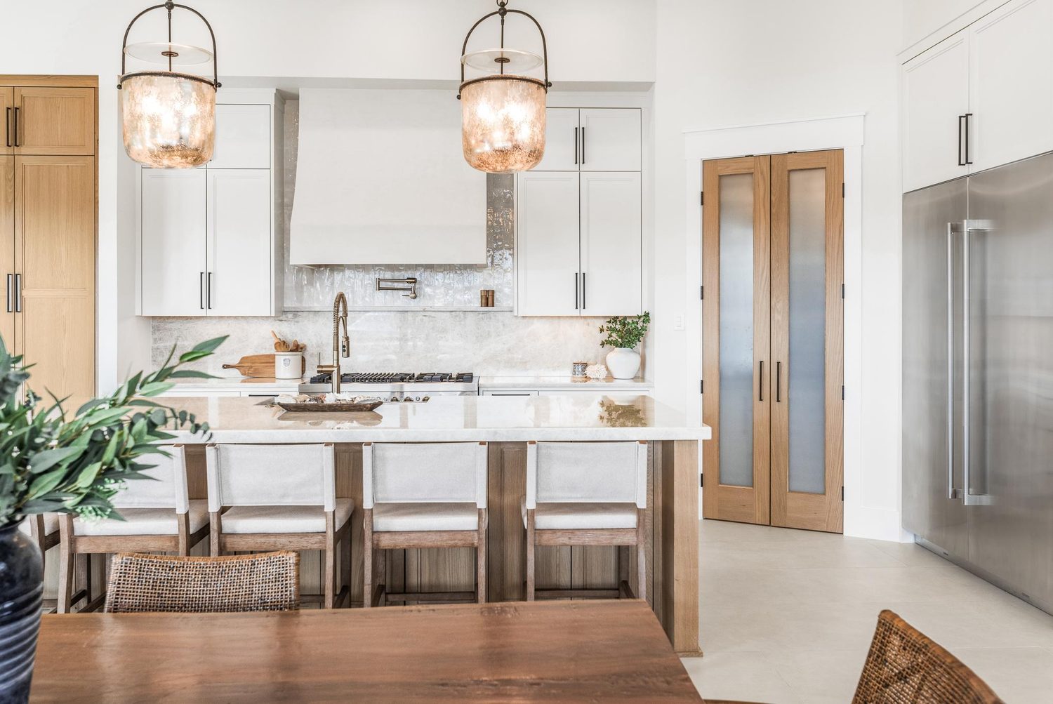 White kitchen with marble backsplash and brass pot filler