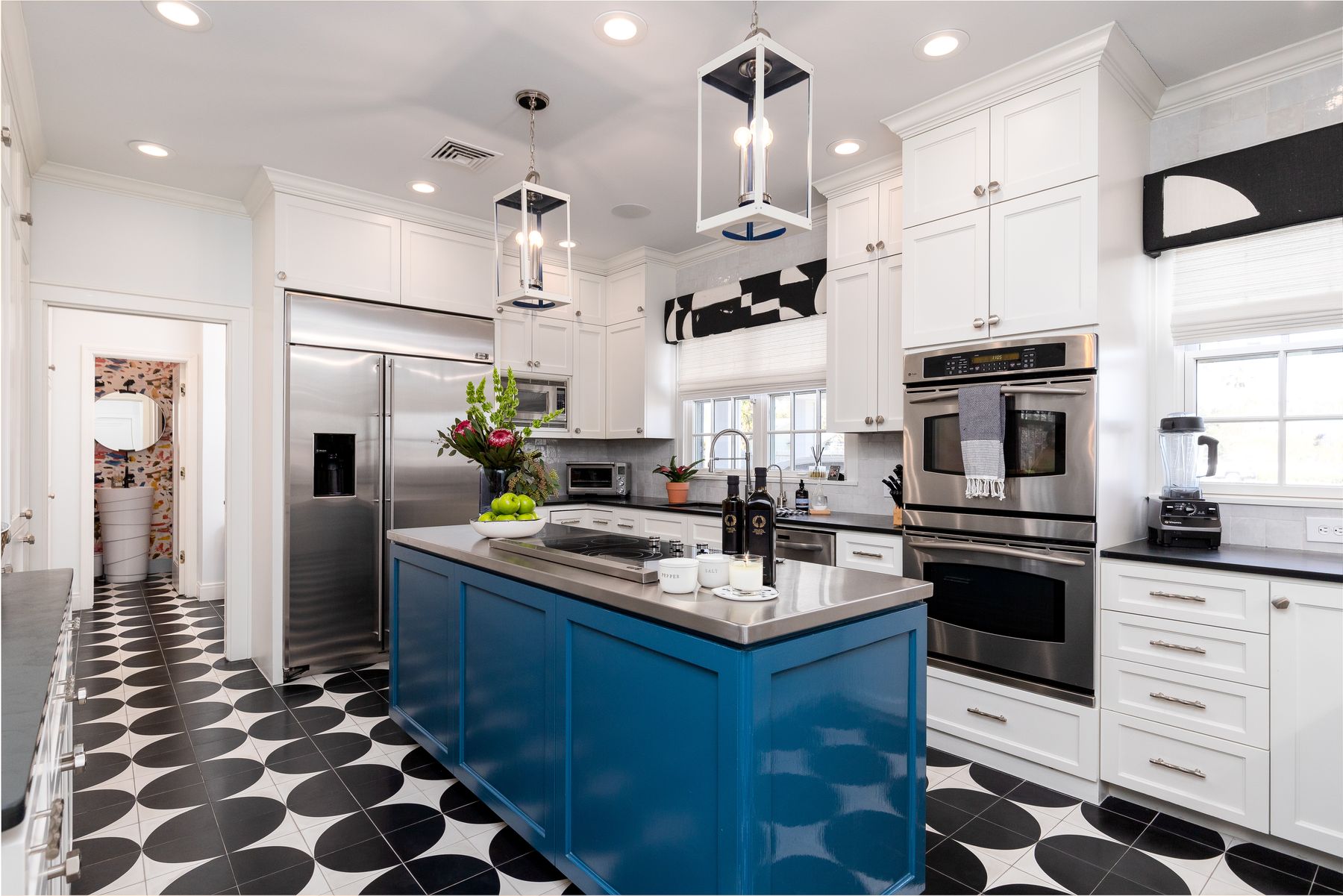 A remodeled kitchen with a deep blue island and a black-and-white patterned floor