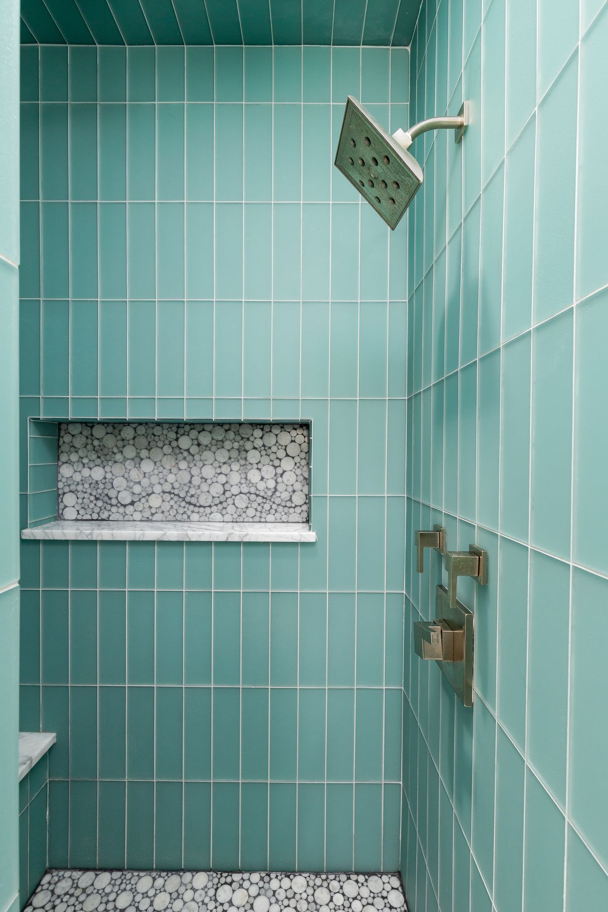 Shower with sea-glass green tile and a stone mosaic niche