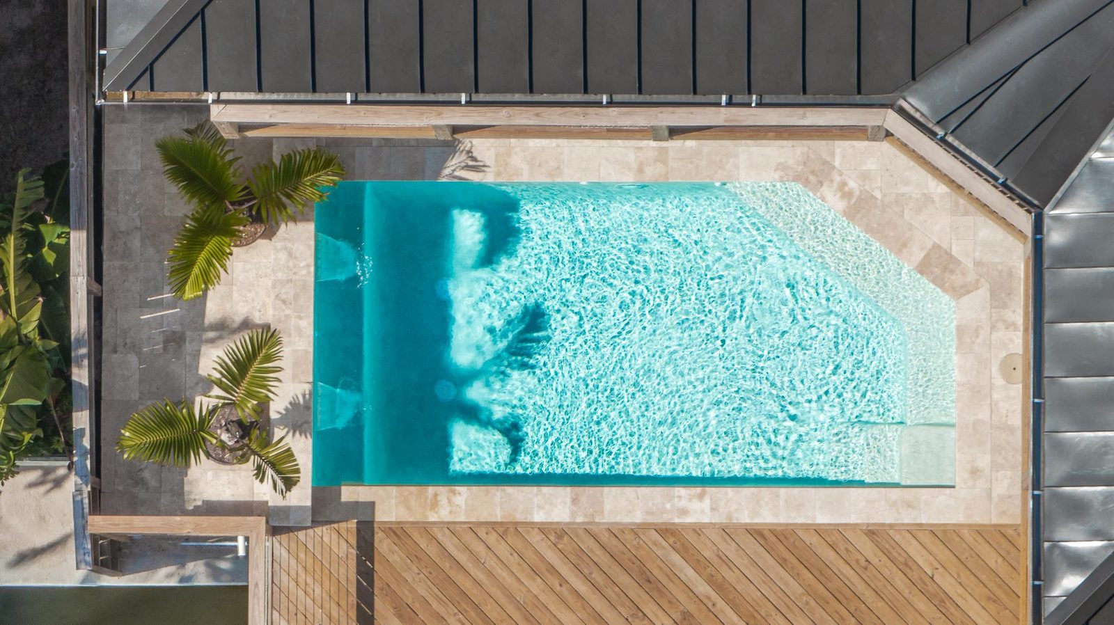 Overhead view of a turquoise pool set into a travertine deck