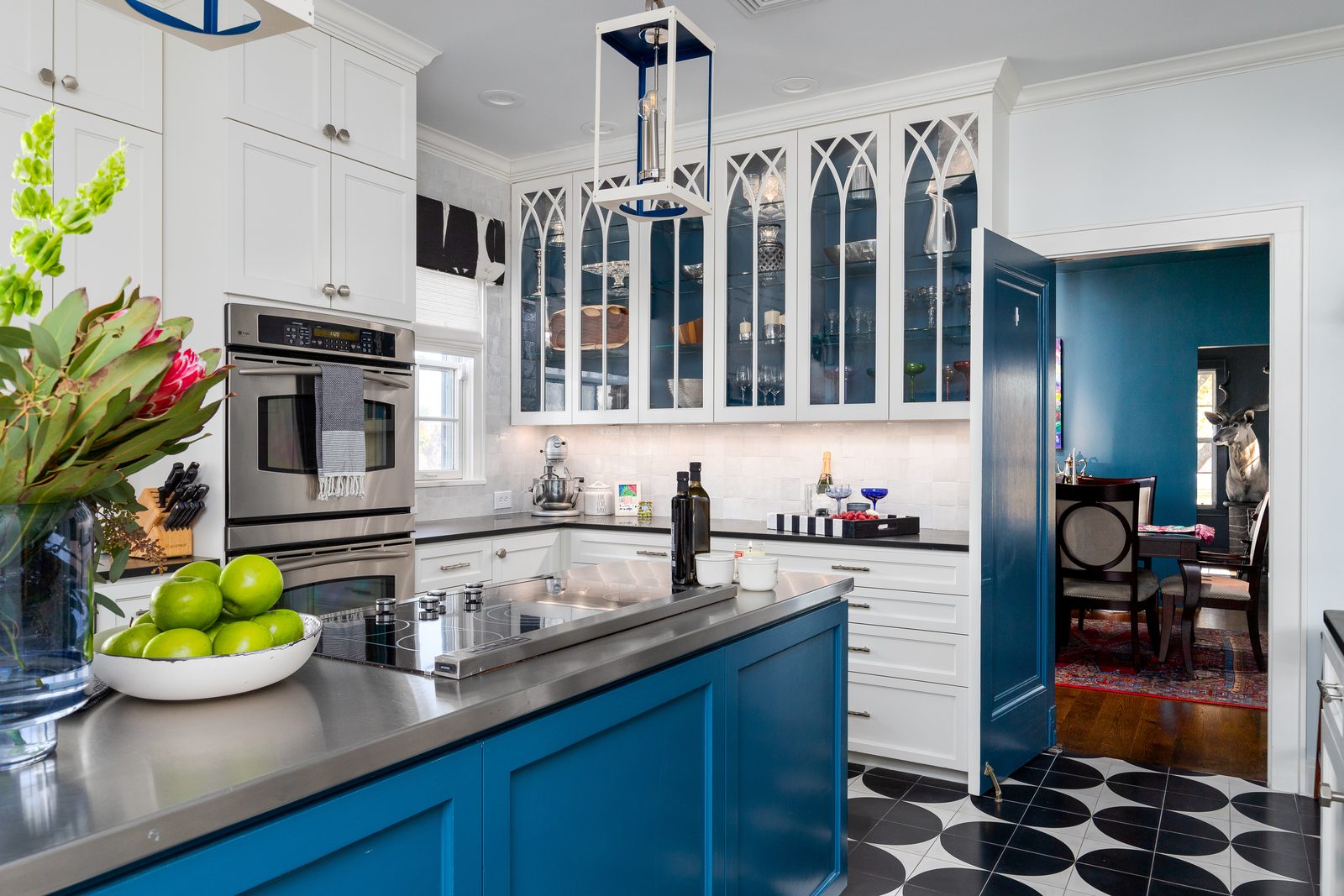 A remodeled kitchen with a blue island, white cabinetry and checkerboard floor
